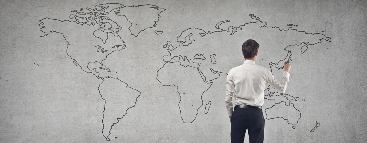 A man drawing on a world map sketched on a wall